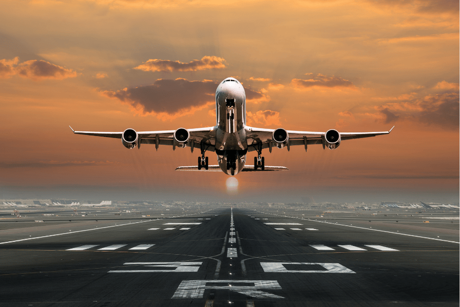 Passenger jet taking off from a runway into a sunset sky