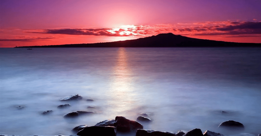 Rangitoto Island's volcanic cone silhouetted at sunrise across the Hauraki Gulf