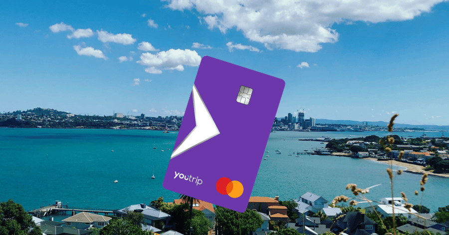 A purple YouTrip Mastercard held against an Auckland harbour backdrop
