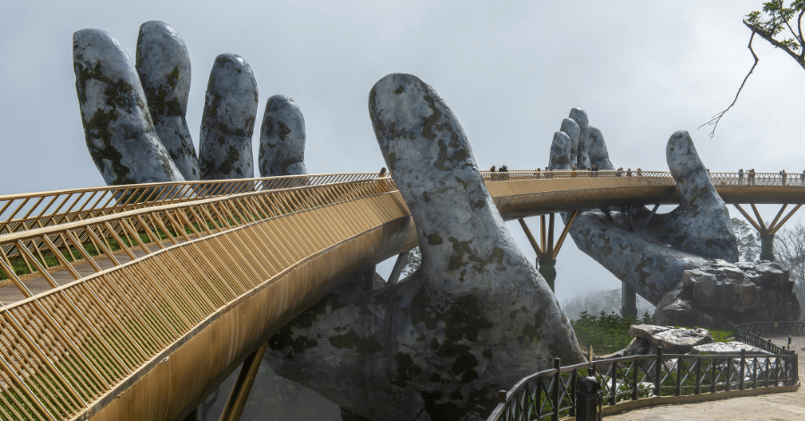 The Golden Bridge at Ba Na Hills held up by two giant stone hands in mist