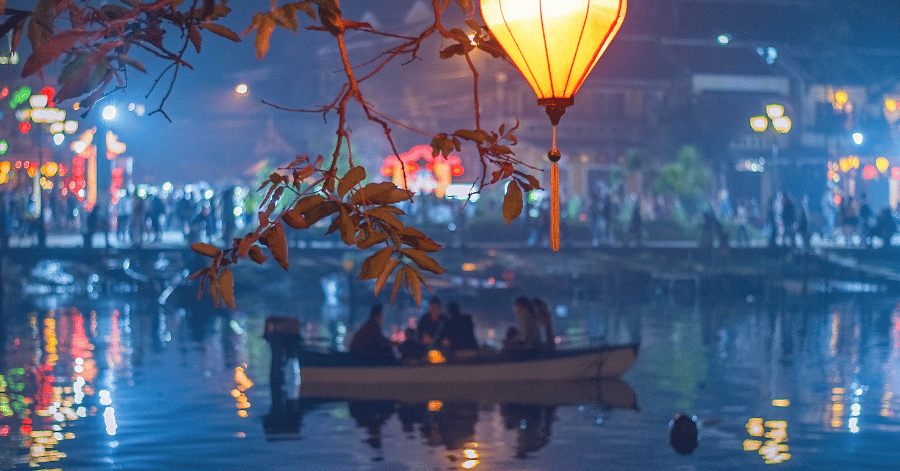 Silk lanterns and a wooden sampan reflected on the river in Hoi An at night