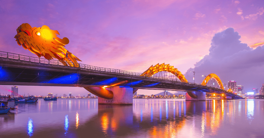 Da Nang's Dragon Bridge lit gold at dusk, reflected in the Han River