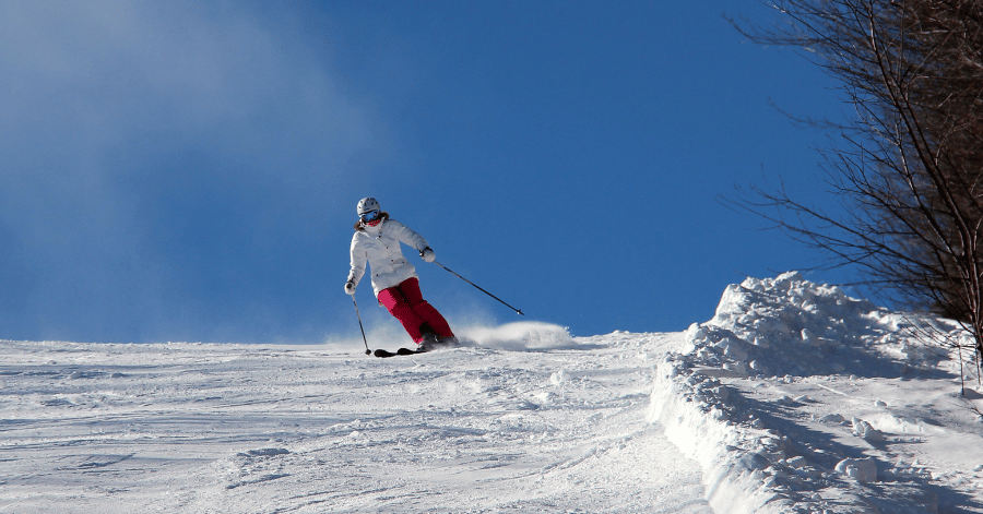 Skier carving down a fresh powder snow slope on a clear winter day