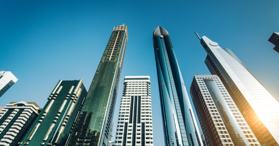 Low-angle view of modern glass-tower skyscrapers in a business district against a clear blue sky