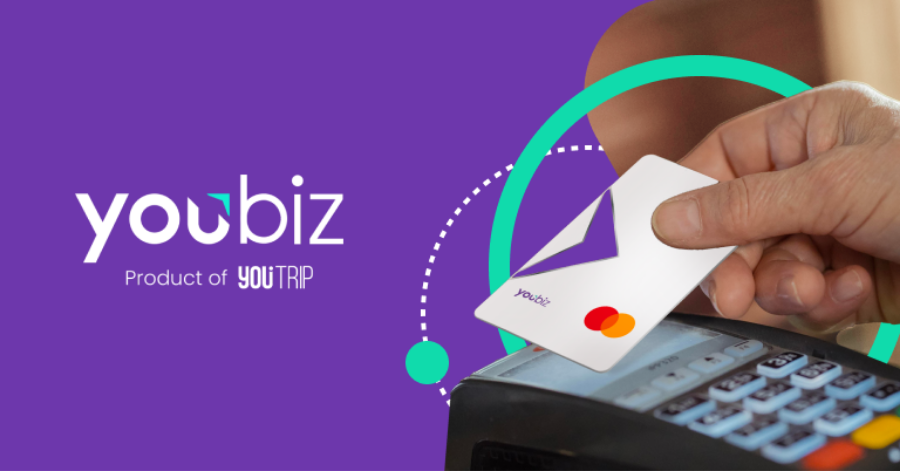 Hand tapping a white YouBiz Mastercard contactlessly on a card payment terminal