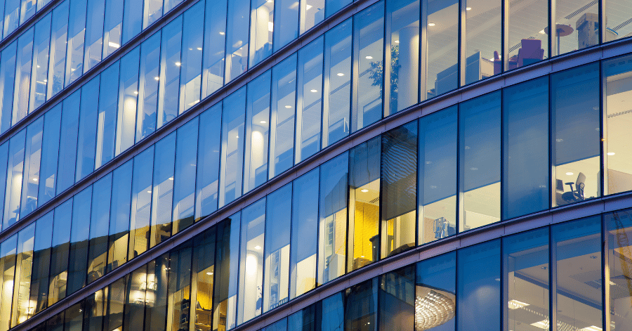 Curved glass facade of a modern corporate office building lit up at dusk