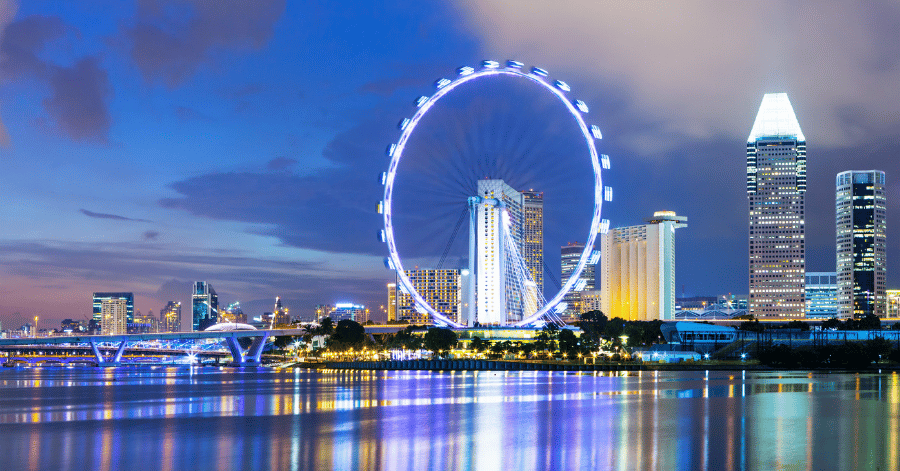 The Singapore Flyer observation wheel lit up at dusk, with the Marina Bay skyline reflected on the water