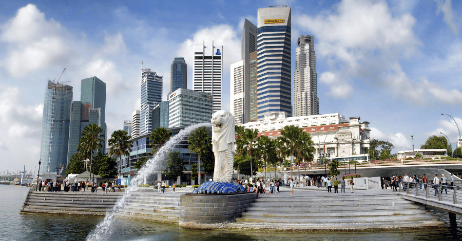 The Merlion spouting water into Marina Bay with Singapore's Raffles Place office towers behind
