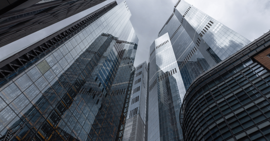 Glass office towers in Singapore's central business district viewed from below against a cloudy sky