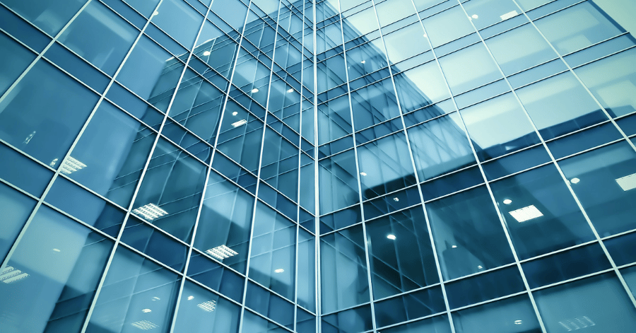 Low-angle view of a blue glass office tower with reflections across its windows