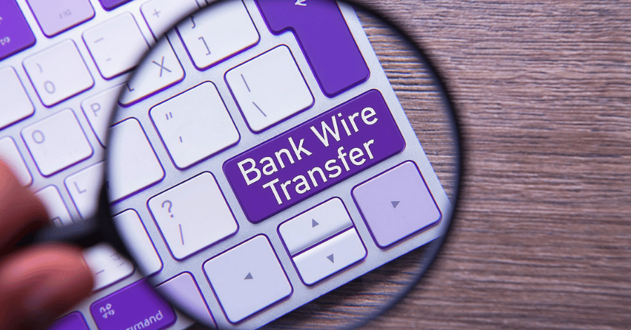 Magnifying glass highlighting a purple keyboard key labelled Bank Wire Transfer