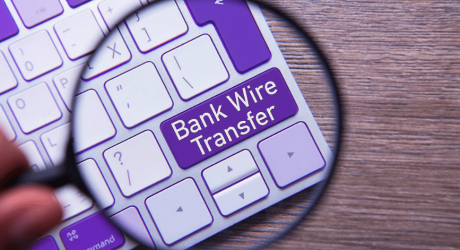 Magnifying glass highlighting a purple keyboard key labelled Bank Wire Transfer