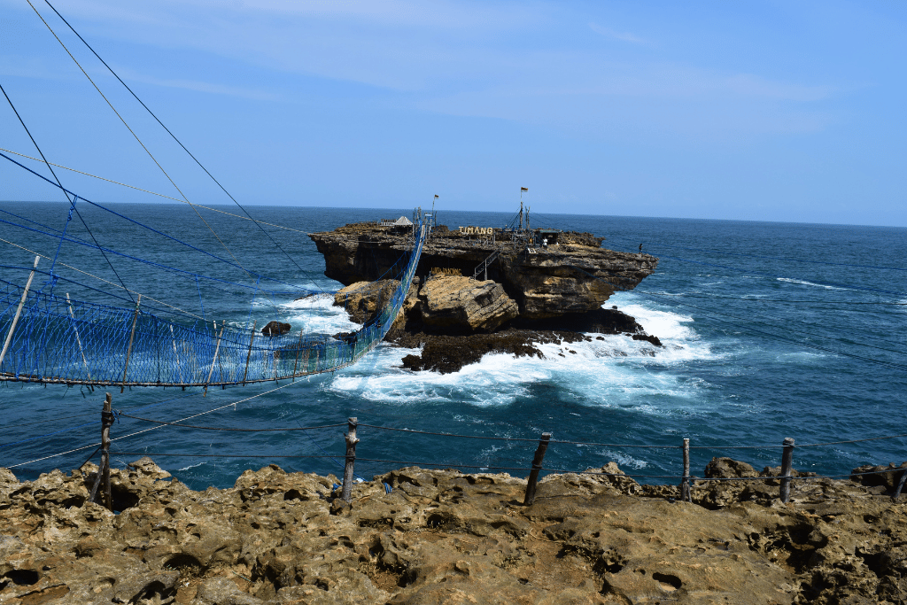 The rope crossing to Timang Beach's rocky islet above the churning surf