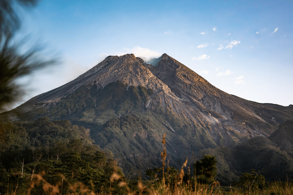 Mount Merapi's forested volcanic cone under a clear blue sky near Yogyakarta
