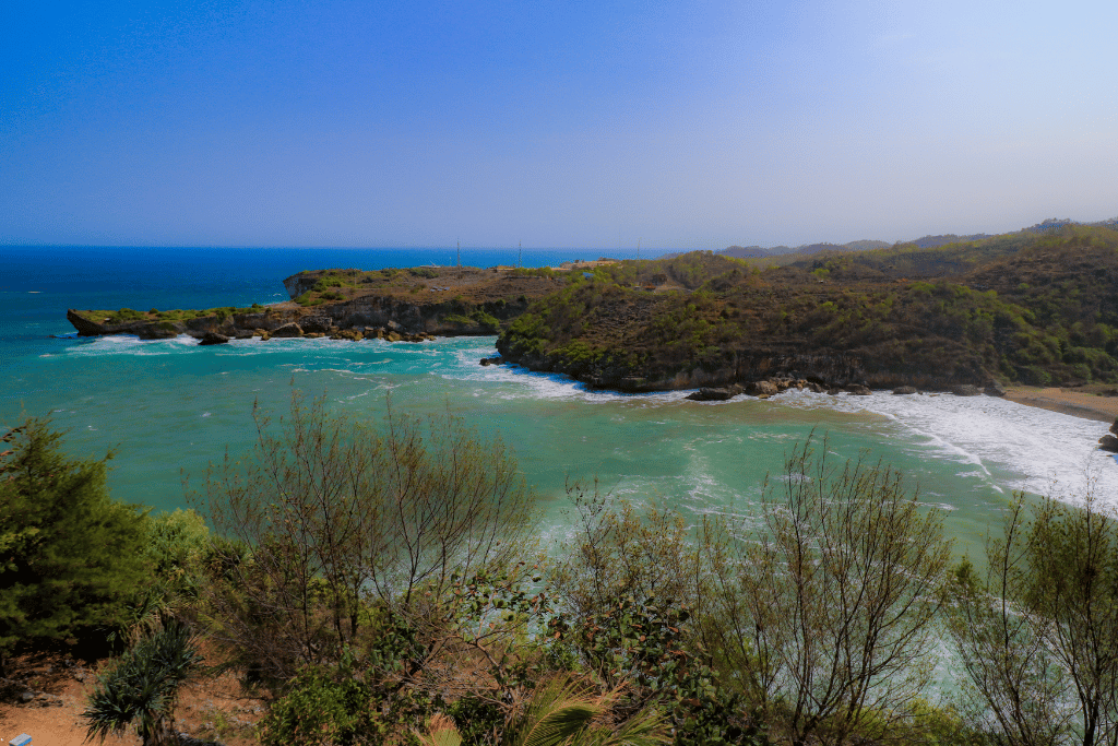 A turquoise Gunungkidul bay ringed by limestone cliffs and white surf