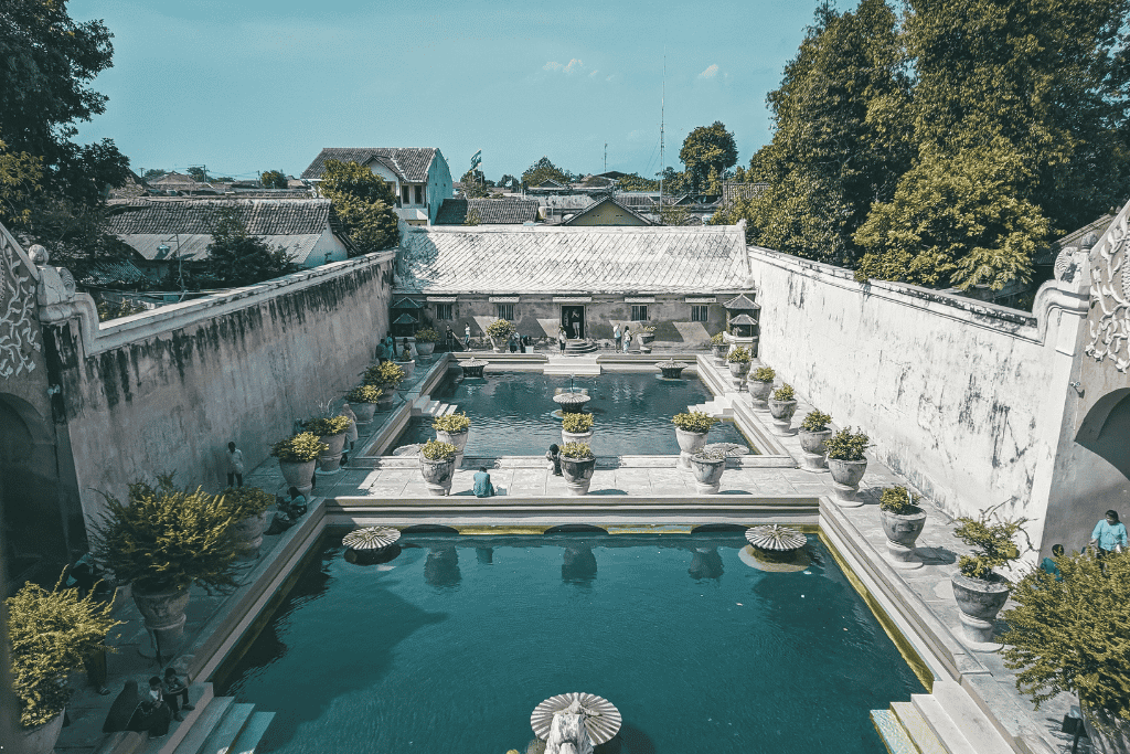 The turquoise bathing pools of Taman Sari water castle, ringed by white walls and potted plants
