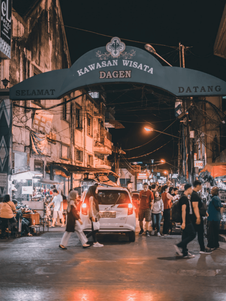 A lit welcome arch over a busy Yogyakarta tourist street at night, near Malioboro