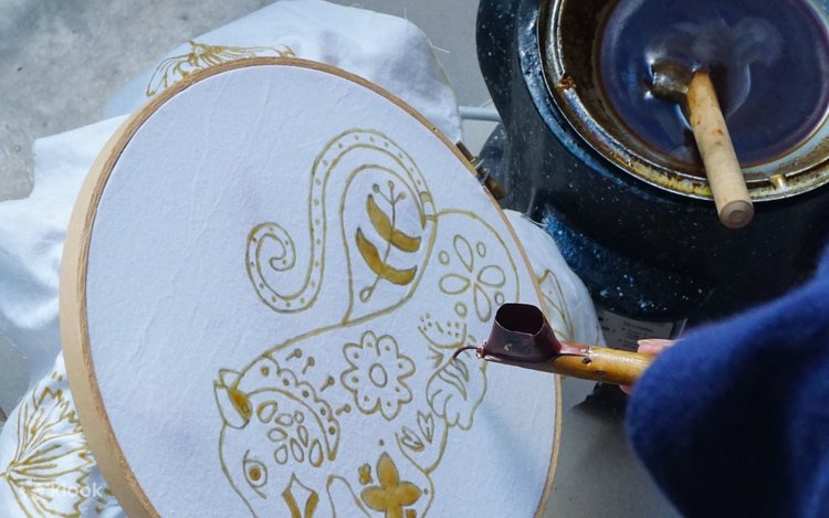Hot wax applied with a canting tool to draw a batik pattern on cloth