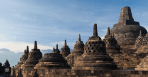 Bell-shaped stupas crowning Borobudur temple at sunrise, with misty hills behind