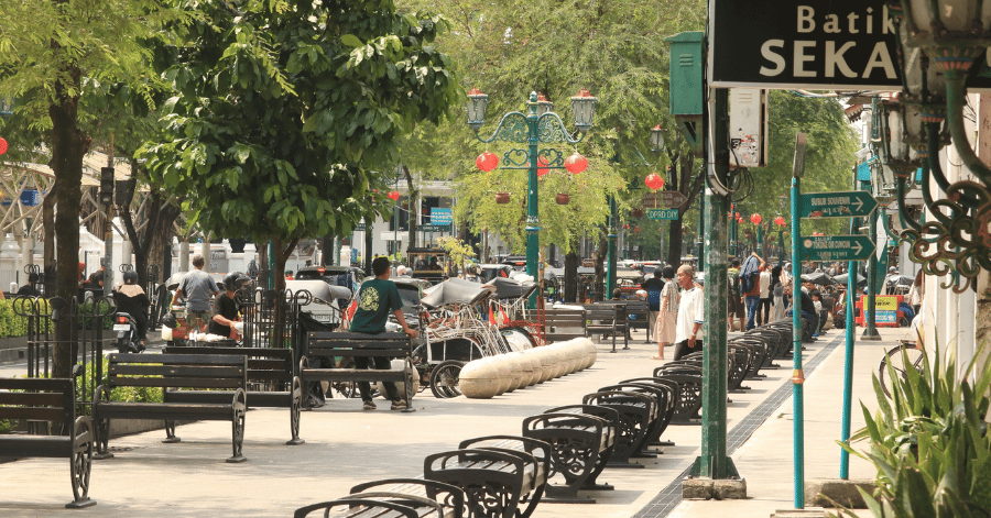 The tree-lined pedestrian stretch of Malioboro Street with benches, lanterns and a becak