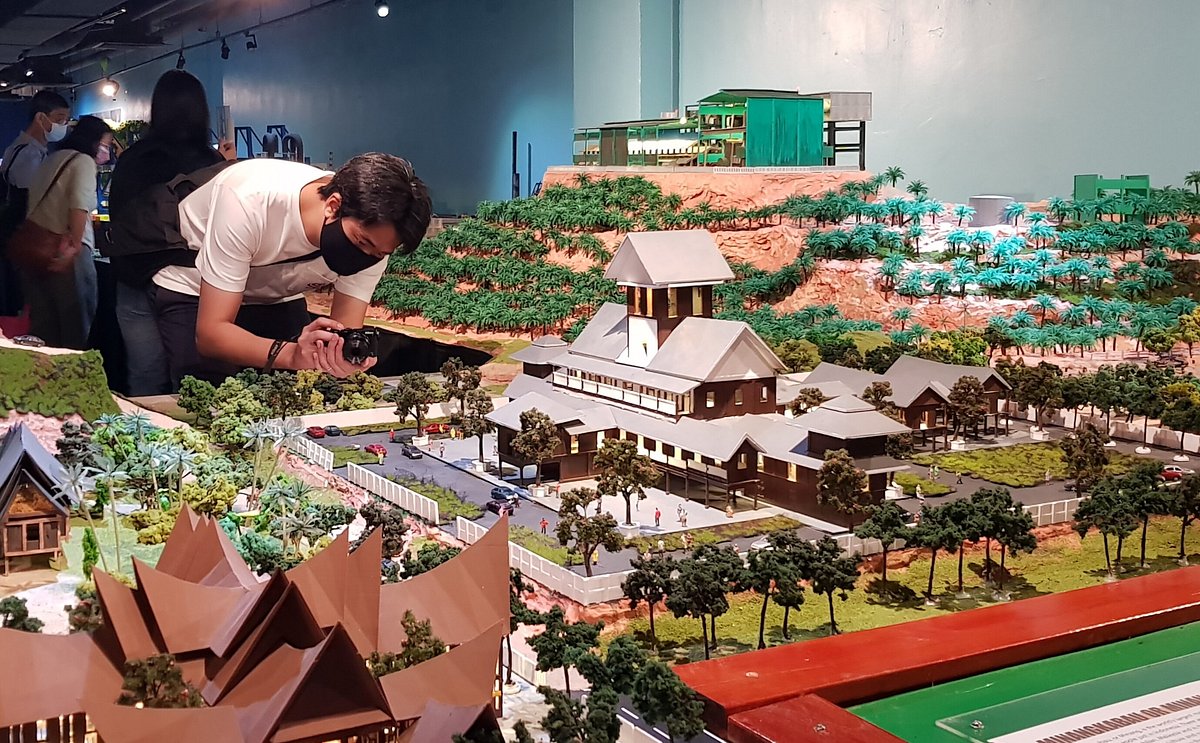 Visitor photographing detailed miniature building models at MinNature Malaysia