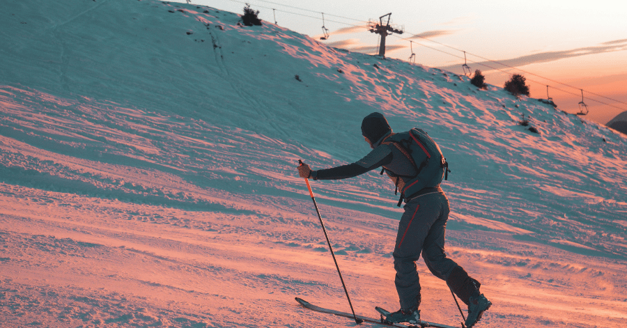 Skier climbing a snow-covered slope at sunset with a ski lift behind, during winter in Korea