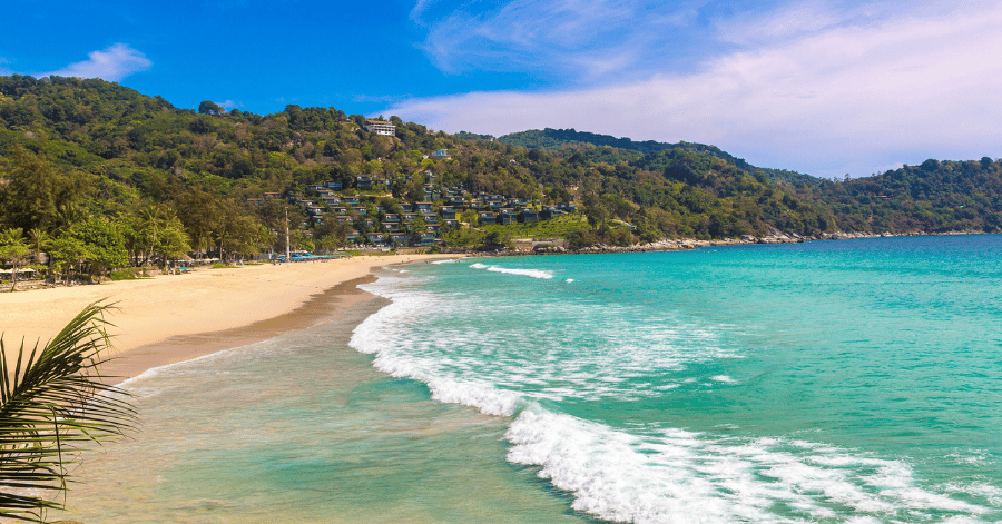 The curving sandy bay of Kata Noi Beach backed by green hills and hillside resorts