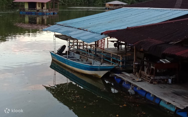 Wooden boats moored beside a tin-roofed jetty on a calm river at dusk