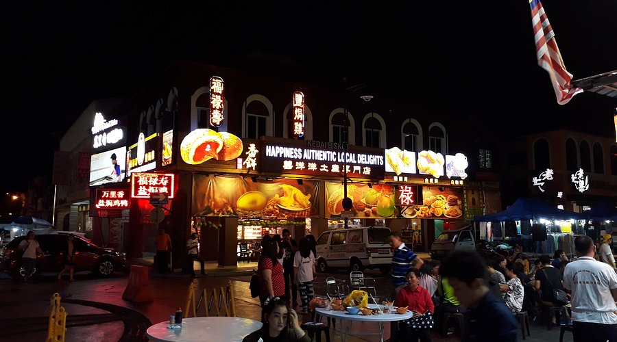 A lit night-time food street in Ipoh's New Town with diners at outdoor tables