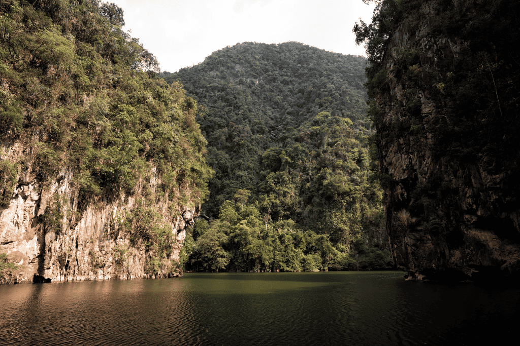 The still green water of Tasik Cermin enclosed by jungle-covered limestone cliffs near Ipoh