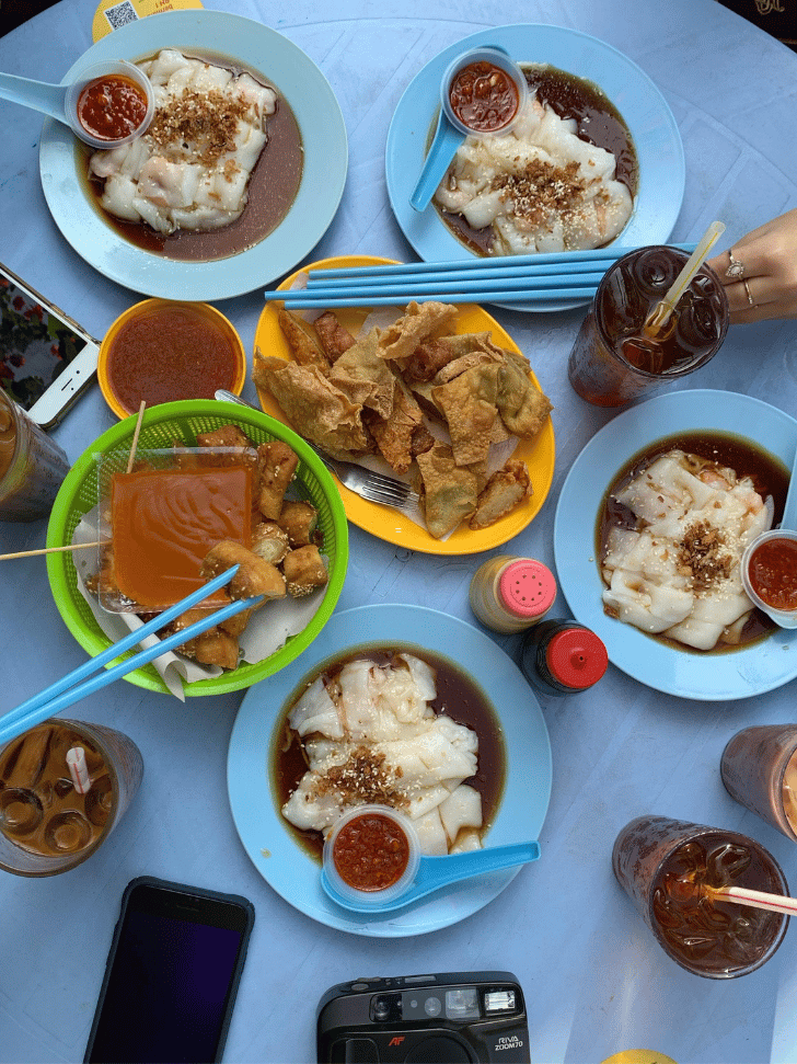 An overhead spread of Ipoh chee cheong fun, fried wontons and iced drinks on a table