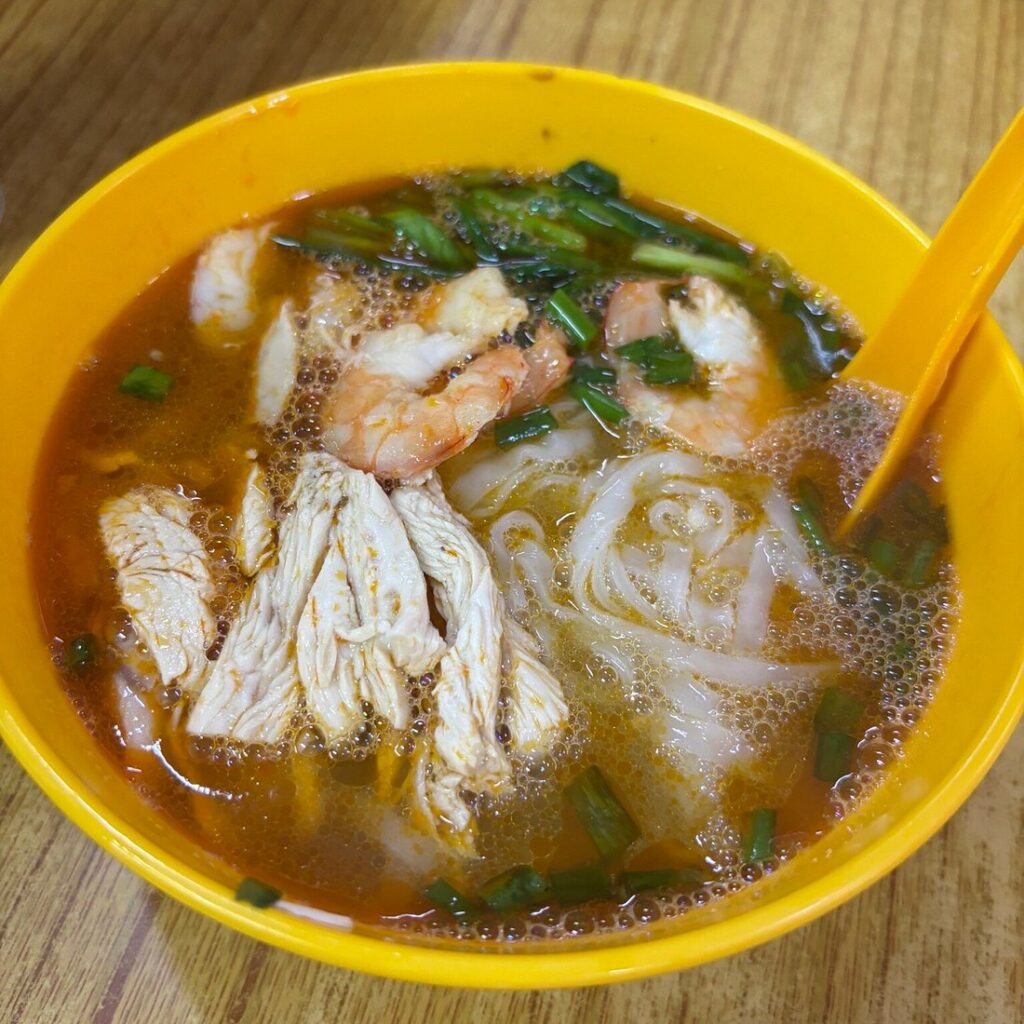 A bowl of Ipoh hor fun: flat rice noodles in prawn broth topped with chicken, prawns and spring onion