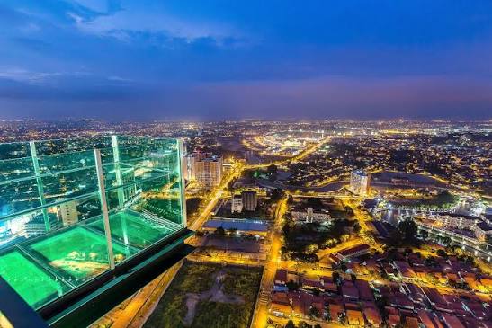Night-time aerial view over Malacca's lights from the glass-floor Shore Sky Tower deck