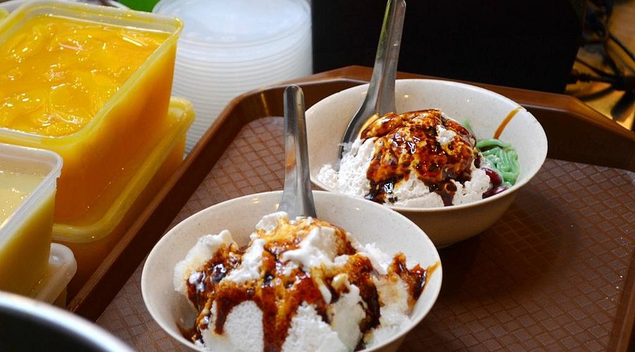 Two bowls of shaved-ice cendol topped with gula melaka syrup on a tray at Jonker 88
