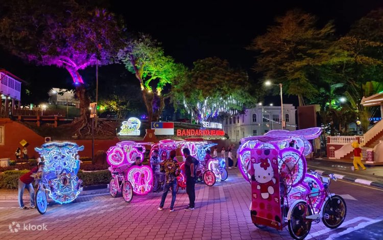 Brightly lit neon-decorated tourist trishaws parked at night near Dutch Square
