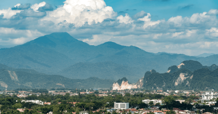 Ipoh city rooftops with jungle-covered limestone hills and mountains rising behind