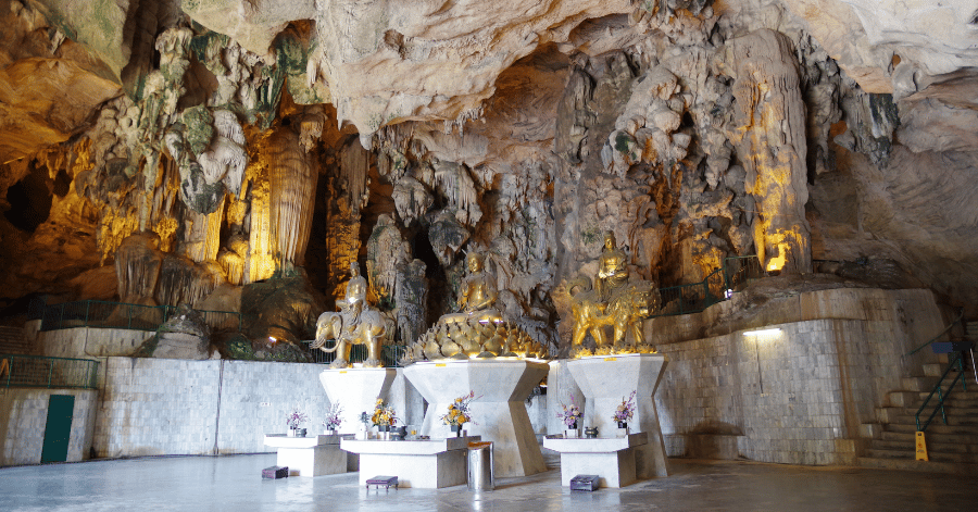 Golden Buddhist statues on altars inside the vast limestone cavern of Kek Lok Tong, Ipoh