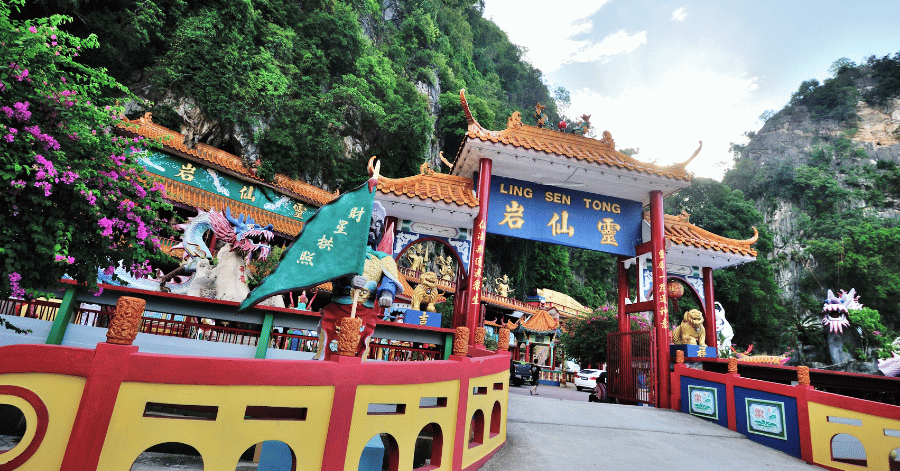 The colourful dragon-topped entrance archway of Ling Sen Tong temple below limestone hills