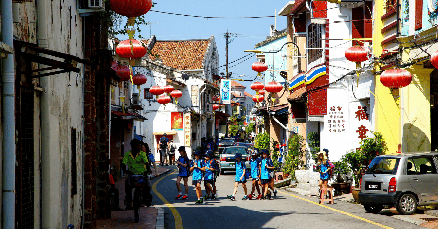 A quiet Jonker Street by day, hung with red lanterns between heritage shophouses