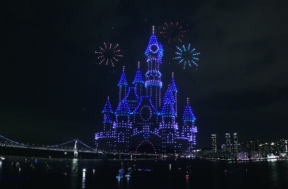 Drone light show forming a glowing blue castle over Gwangalli Beach with fireworks