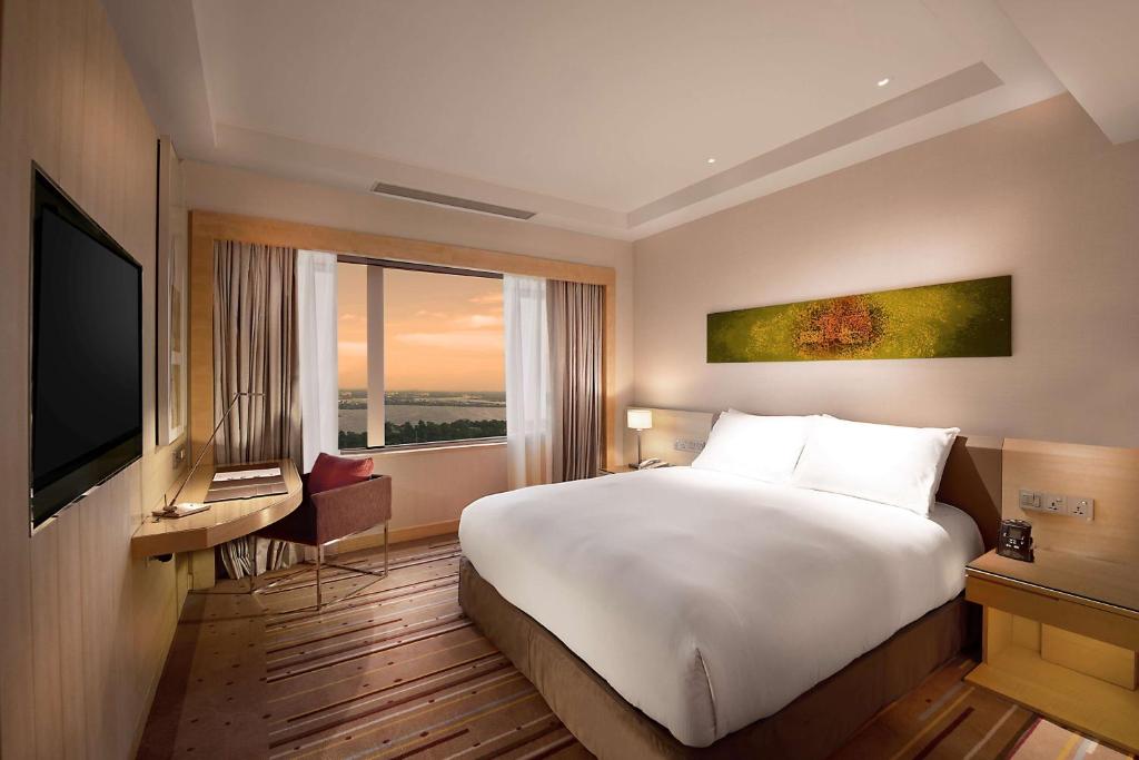 DoubleTree by Hilton room with a white bed and a window overlooking water at sunset