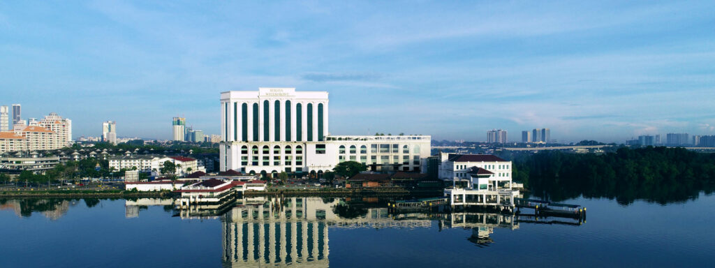 Berjaya Waterfront Hotel's white colonnaded facade reflected in the water at Stulang Laut