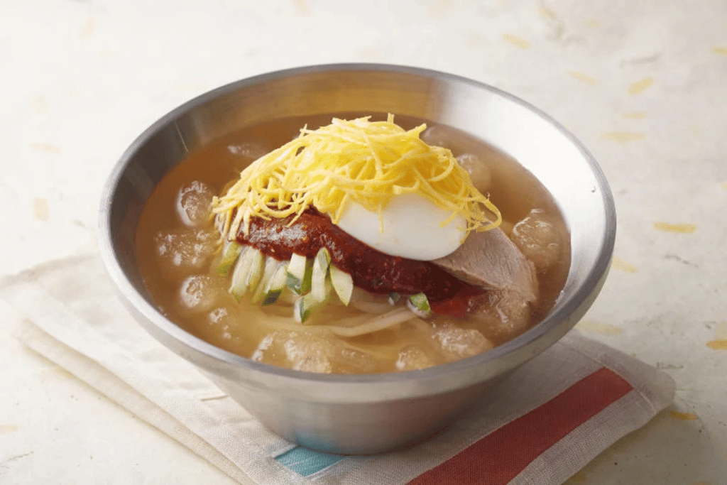 Bowl of milmyeon cold wheat noodles topped with egg and vegetables