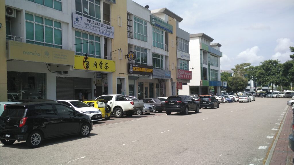 Row of shophouse eateries with cars parked along a street in Taman Molek, JB
