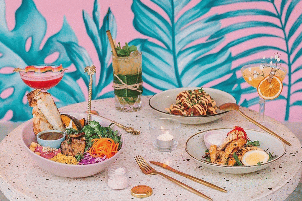 Colourful vegan bowls and drinks on a pink tropical table at a Bali cafe