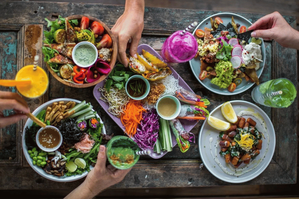 Overhead view of hands sharing colourful vegetarian dishes at a Canggu cafe