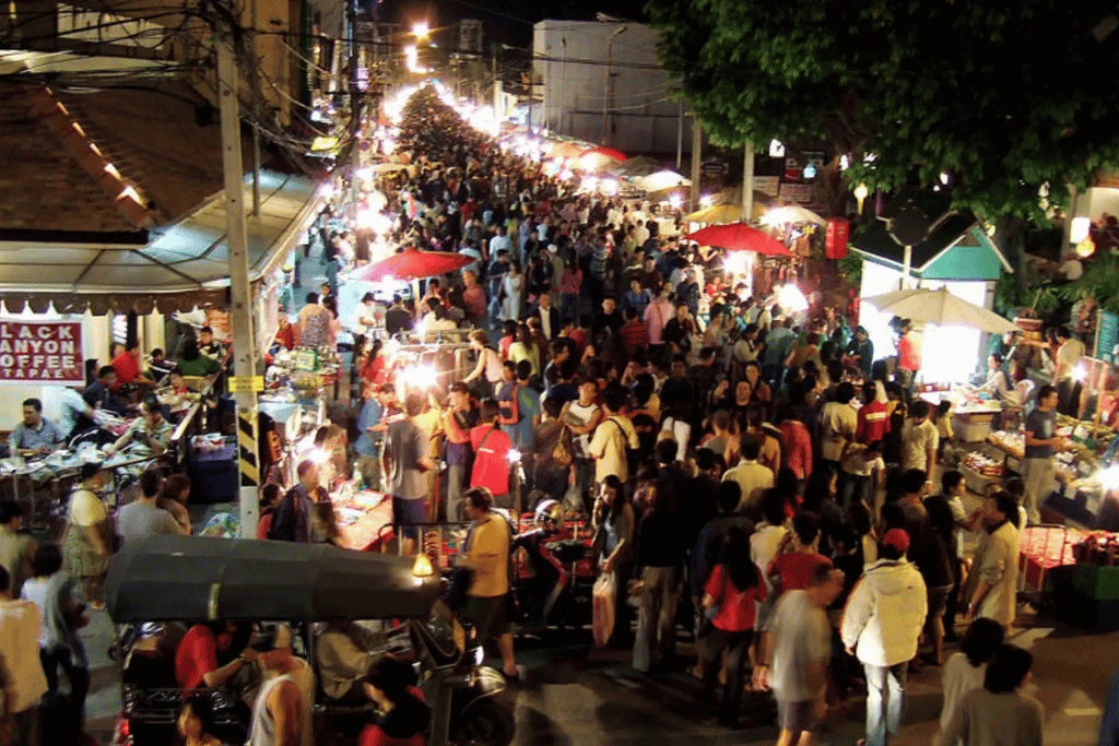 Crowds browsing stalls along a busy lantern-lit Bali night market street