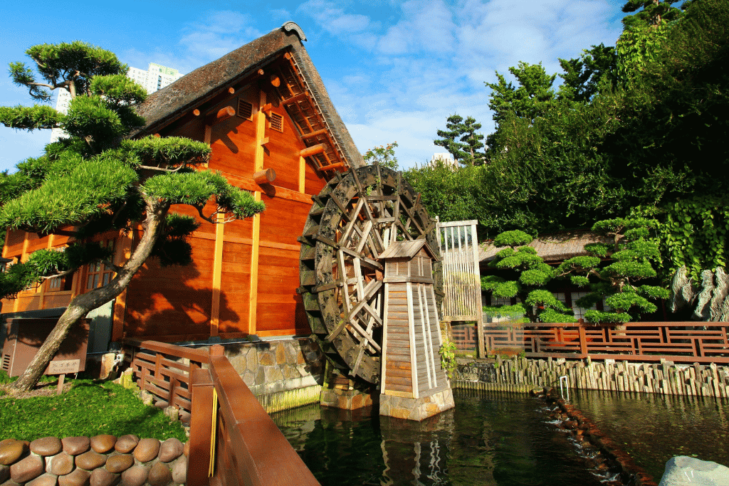 A golden wooden pavilion and water wheel in the manicured Tang-style Nan Lian Garden, Kowloon