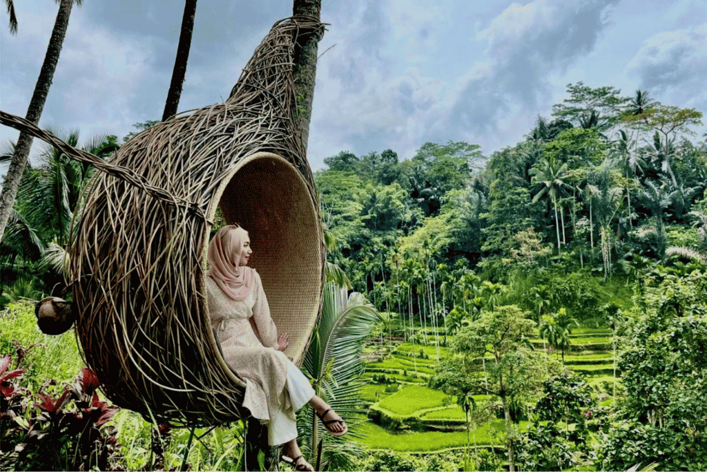 Person in a woven nest swing above the green Tegalalang rice terraces, Ubud