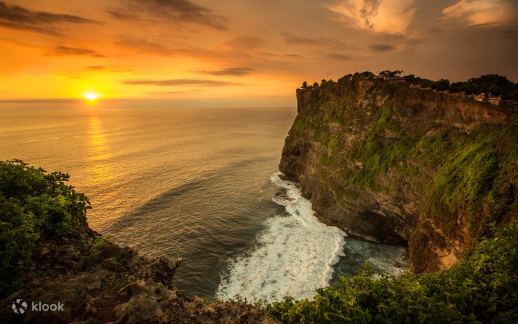 Uluwatu's cliffs glowing above the ocean and surf at sunset, Bali